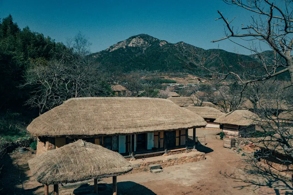 Thatched houses of the walled town below a green hill — Naganeupseong, Suncheon