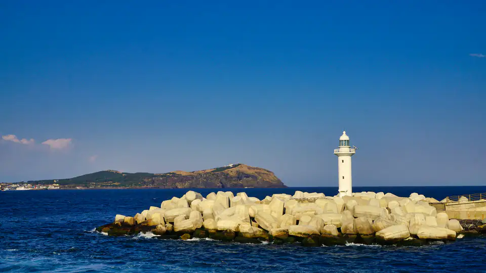 A white lighthouse on the rocky shore of Udo — Udo, Jeju